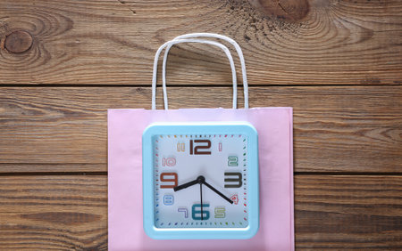 Alarm clock with shopping bag on wooden background. top viewの写真素材