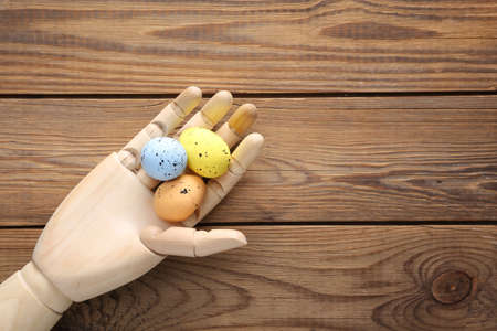 Wooden hand holding easter eggs on wooden background