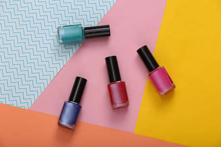 Bottles of colored nail polish on a colored background. top view