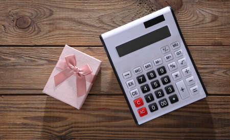 Calculator with gift box on wooden background. top viewの写真素材