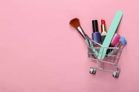 Beauty products in shopping trolley on pink pastel background.の写真素材