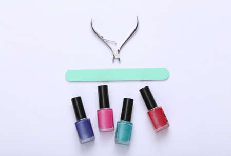 Manicure accessories. Nail polish bottles, scissors and nail file on white background. top view....