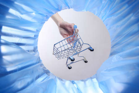 Hand throws shopping trolley into trash bin with package. inside viewの写真素材