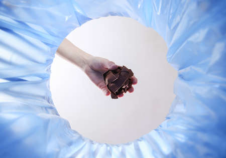 Wooden hand throws crumpled ball of paper into trash bin with package. inside viewの写真素材