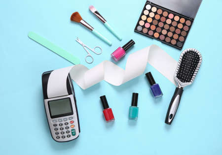 Payment pos terminal and make-up products on a blue background