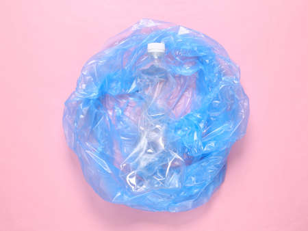 Trash bag with plastic bottle on pink background