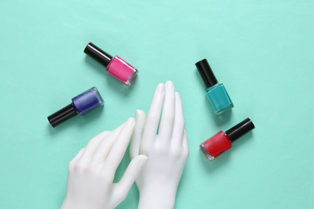 White mannequin hands and bottles of nail polish on blue backgroundの写真素材
