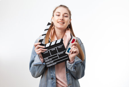 Young emotional woman holding clapperboard and 3d glasses on white backgroundの写真素材