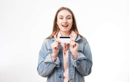Young contented woman holding credit card on white background