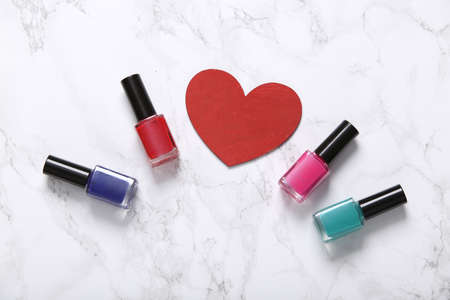 Nail polish bottles and heart on marble backgroundの写真素材