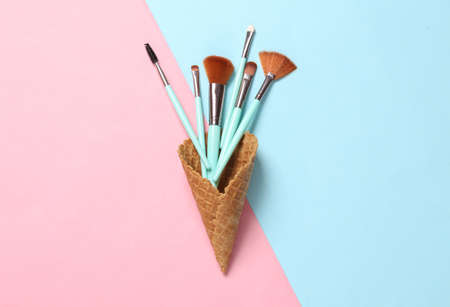 Waffle cones with makeup brushes on pink blue pastel background. creative beauty layoutの写真素材