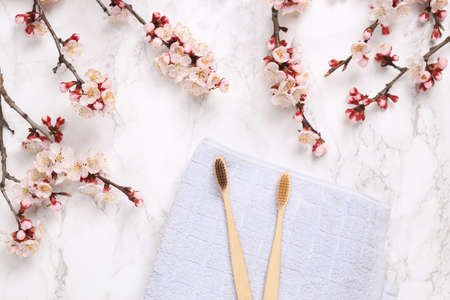 Personal care, hygiene supplies with beautiful flowering branches. Eco toothbrushes on marble backgroundの写真素材