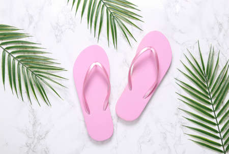 Flip flops on a marble background with palm leaves. summer rest conceptの写真素材