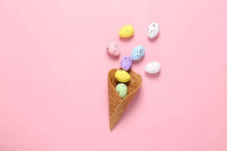 Colored eggs in waffle cone on pink blue background. creative easter layout