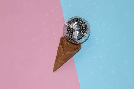 Disco ball ice cream in waffle cone on pink blue background. Minimal holiday party concept. creative...