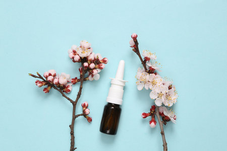 Nasal spray with beautiful flowering branches on blue background. springtime concept. Flat lay, top viewの写真素材