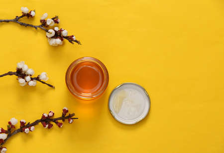 Honey jar with beautiful white flowering branches on yellow background. springtime concept. Flat lay, top view. copy spaceの写真素材