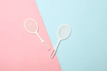 Doll tennis rackets on a blue-pink pastel background. top view
