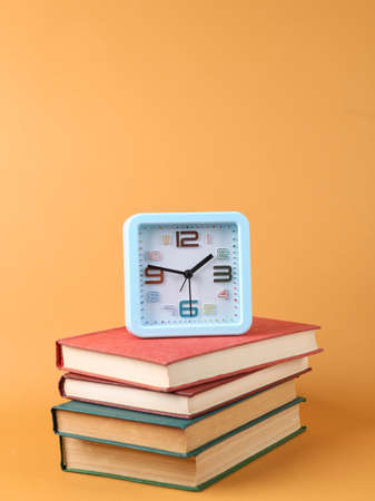 Books and alarm clock on brown background.の写真素材
