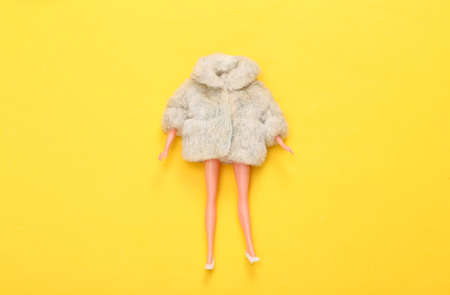 Woman Doll in fur coat and shoes on yellow background. Minimalism fashion layout. top view. flat layの写真素材