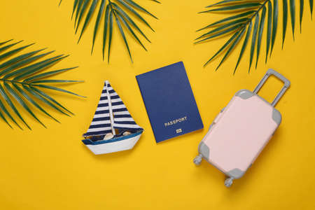 Travel accessories and palm green leaves on yellow background. travel concept. tropical composition. top view. flat layの写真素材