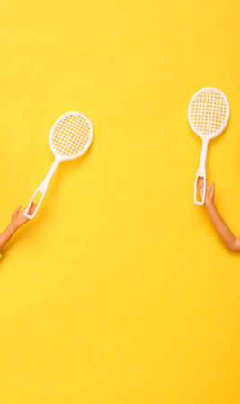 Doll hands holding tennis rackets on yellow background. Minmalism concept art.の写真素材