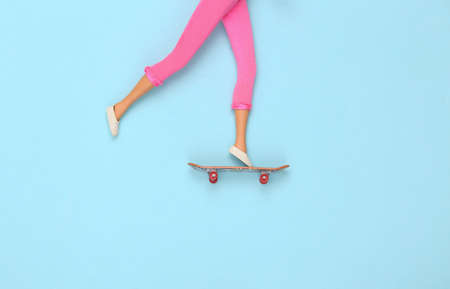Doll legs ride on a skateboard on blue background. minimalismの写真素材