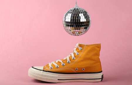 Disco ball and sneaker on pink background. Minimalist party concept