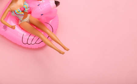 Doll in a swimsuit resting on inflatable flamingo. summer vacation, beach party