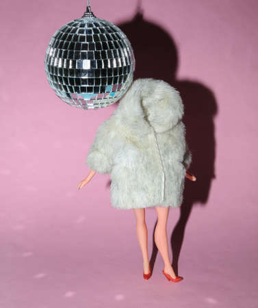 Doll in fur coat and disco ball on a pink bright background. party. concept artの写真素材