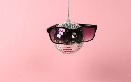 Disco ball with sunglasses on pink background. Minimalist party conceptの写真素材