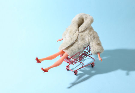 Shopping trolley with Doll mannequin in warm fur coat on blue background. Minimalism fashion shot. concept artの写真素材