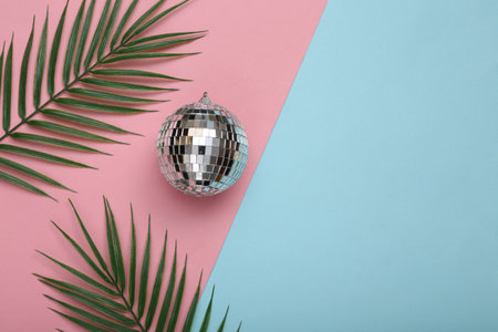 Disco ball with palm leaves on a blue-pink background. top view. flat lay. Minimalist party conceptの写真素材