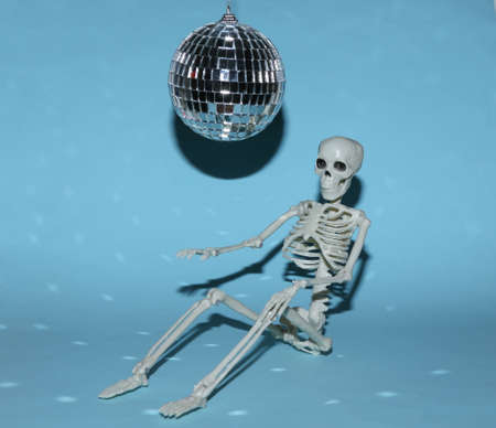 Disco ball and skeleton on blue background. Minimalist party concept