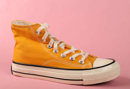 Yellow sneaker on a pink background. minimalism