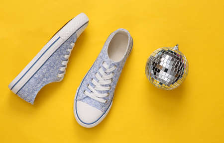 Disco ball with sneakers on yellow background. Minimalist party concept. top viewの写真素材