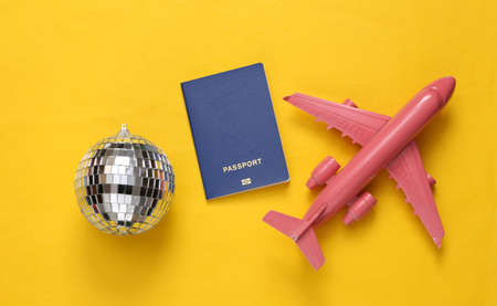 Disco ball with travel accessories on a yellow background. top view. flat lay. Minimalism party and...