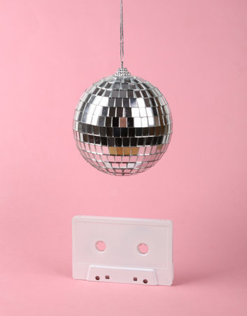Disco ball with retro audio cassette on pink background. Minimalist party conceptの写真素材