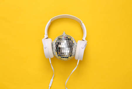 Headphones with Disco ball on yellow background. Minimalism party concept