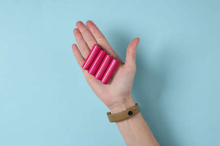 Hand holds aa batteries on blue backgroundの写真素材