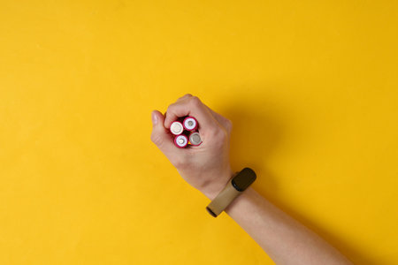 Hand holds aa batteries on yellow backgroundの写真素材