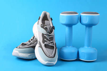 Sports shoes and dumbbells on blue background. fitness concept.の写真素材