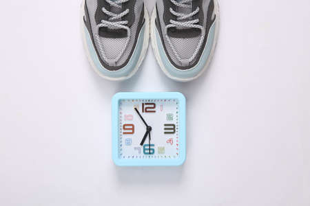 Running shoes and alarm clock on white background. sport concept