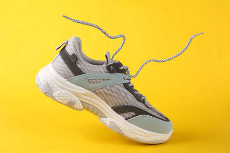 Sports sneaker with flying laces on a yellow background