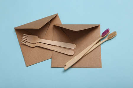 Eco concept. Craft envelope, wooden toothbrushes and forks on blue backgroundの写真素材