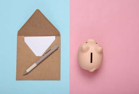 Craft envelope and piggy bank on a blue-pink pastel background. top viewの写真素材