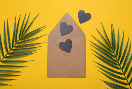 Envelope with hearts on a yellow background with palm leaves. love conceptの写真素材