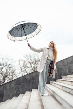 Young stylish girl with umbrella on the stairsの写真素材
