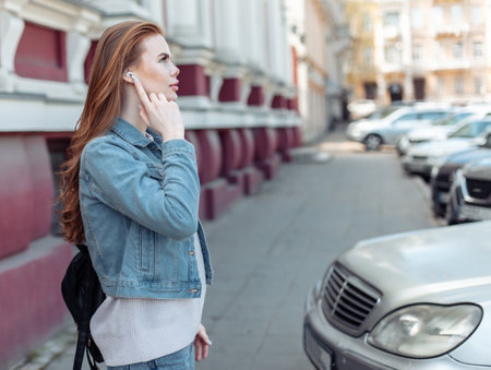 Cute caucasian woman wearing wireless headphones in the cityの写真素材