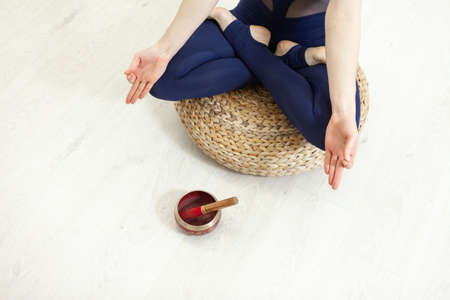 Woman meditating with Tibetan singing bowl in yoga studio. Yoga and healthy lifestyle concept